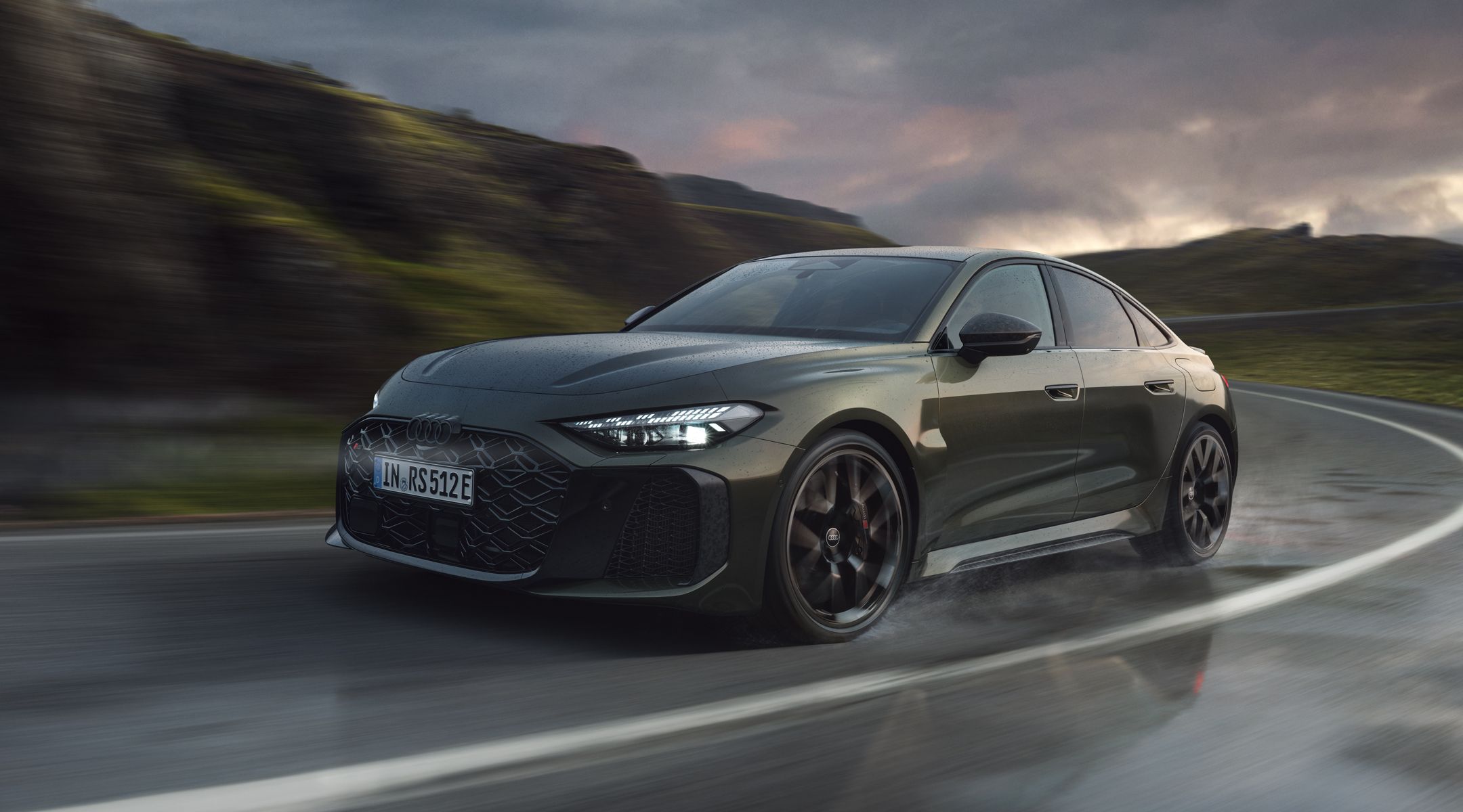 Die RS 5 Limousine schräg von vorn fährt eine Kurve auf einer Gebirgsstraße.